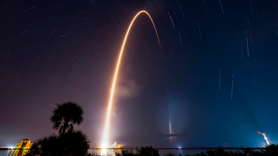 SpaceX launch team posing in front of a Falcon 9 rocket at Cape Canaveral